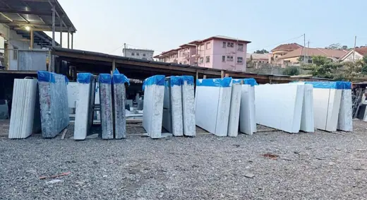 Multiple upright slabs displayed outside a workshop