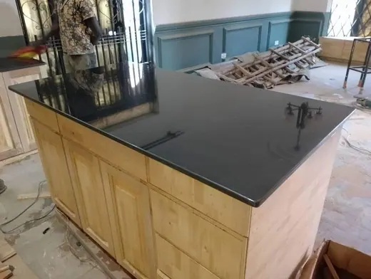 Deep black kitchen island surface above timber cabinets