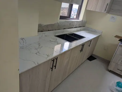 Pale kitchen worktop with inset sink and white cabinets
