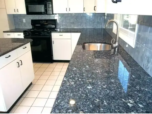 Glossy dark kitchen island with pale cabinetry and a sink behind it