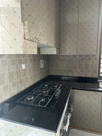 Dark L-shaped kitchen worktop with a hob beneath wall cabinets