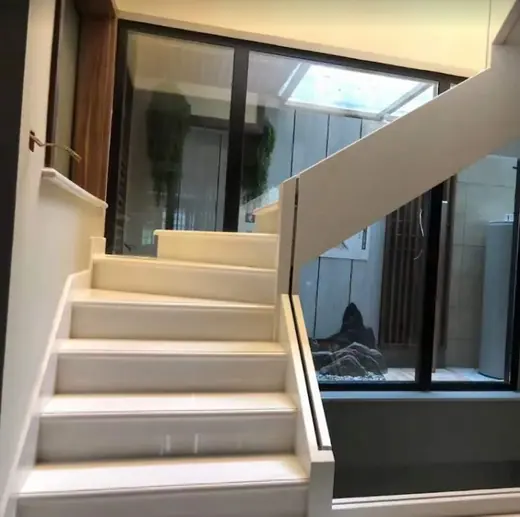 Pale stair treads rising beside a glass railing