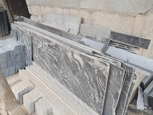 Grey heavily veined slabs leaning in a yard