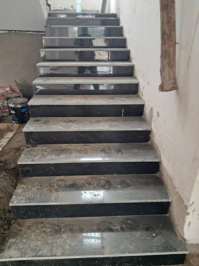 Dark stair treads beside an unfinished interior wall