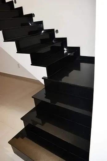 Black open-riser staircase against a pale wall