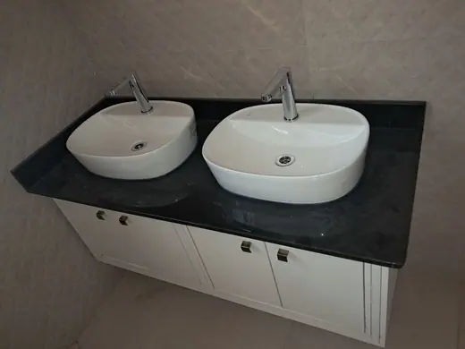 Two white basins set into a dark bathroom vanity top