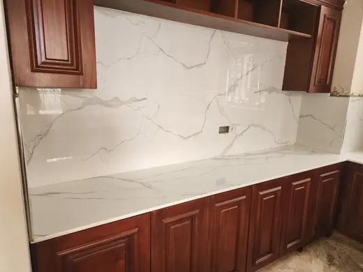 Light veined kitchen worktop beneath timber-framed windows
