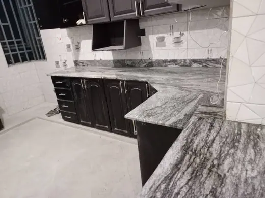 Patterned kitchen worktop above dark cabinets and a tiled wall