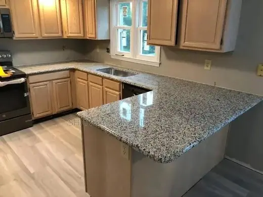 Speckled island worktop in a kitchen with timber cabinets