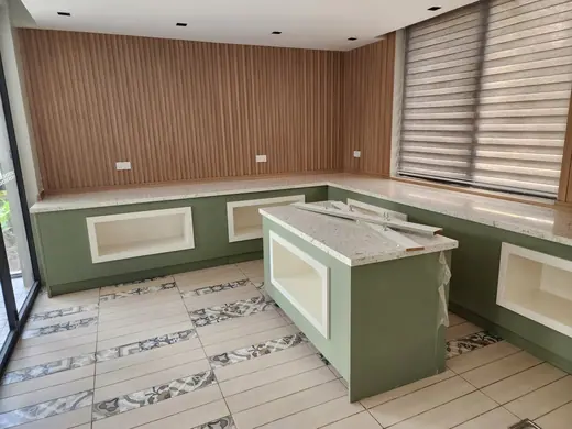 Green and white kitchen with an island ready for its surface
