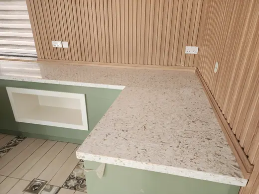 Light speckled island surface with pale green cabinetry